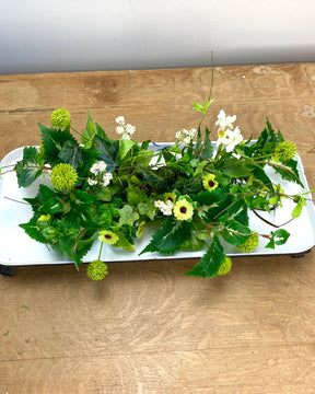 Floral arrangement on a white tray on a wooden surface